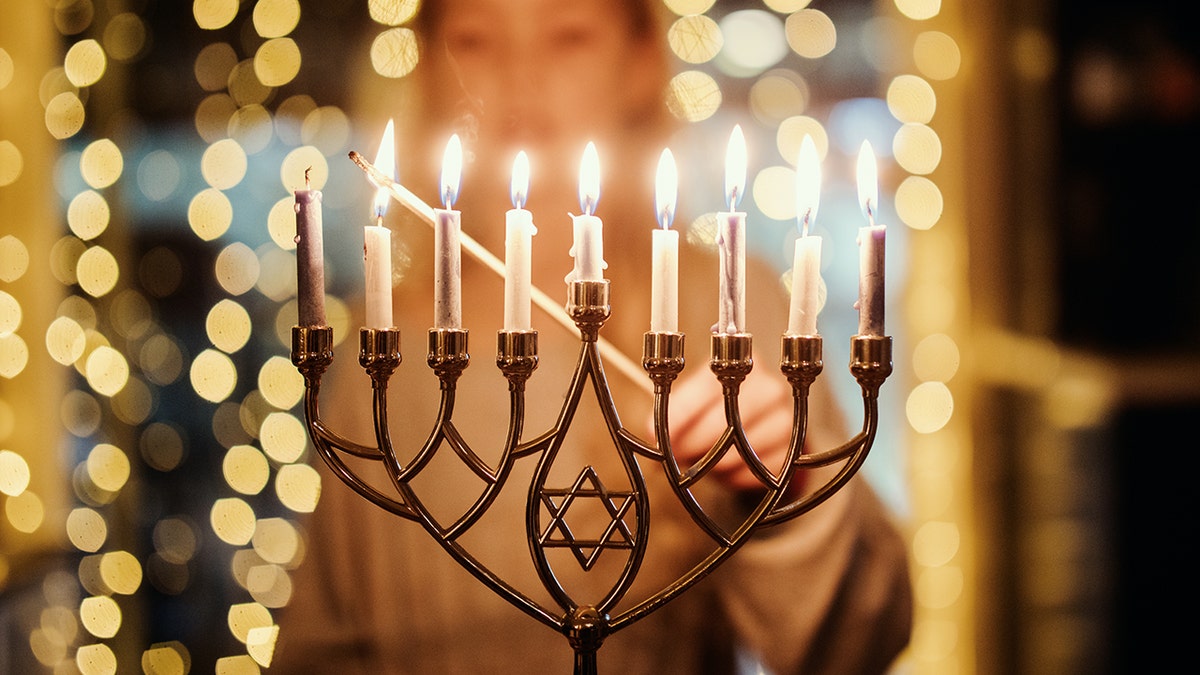 Woman lighting menorah at a public Hanukkah event