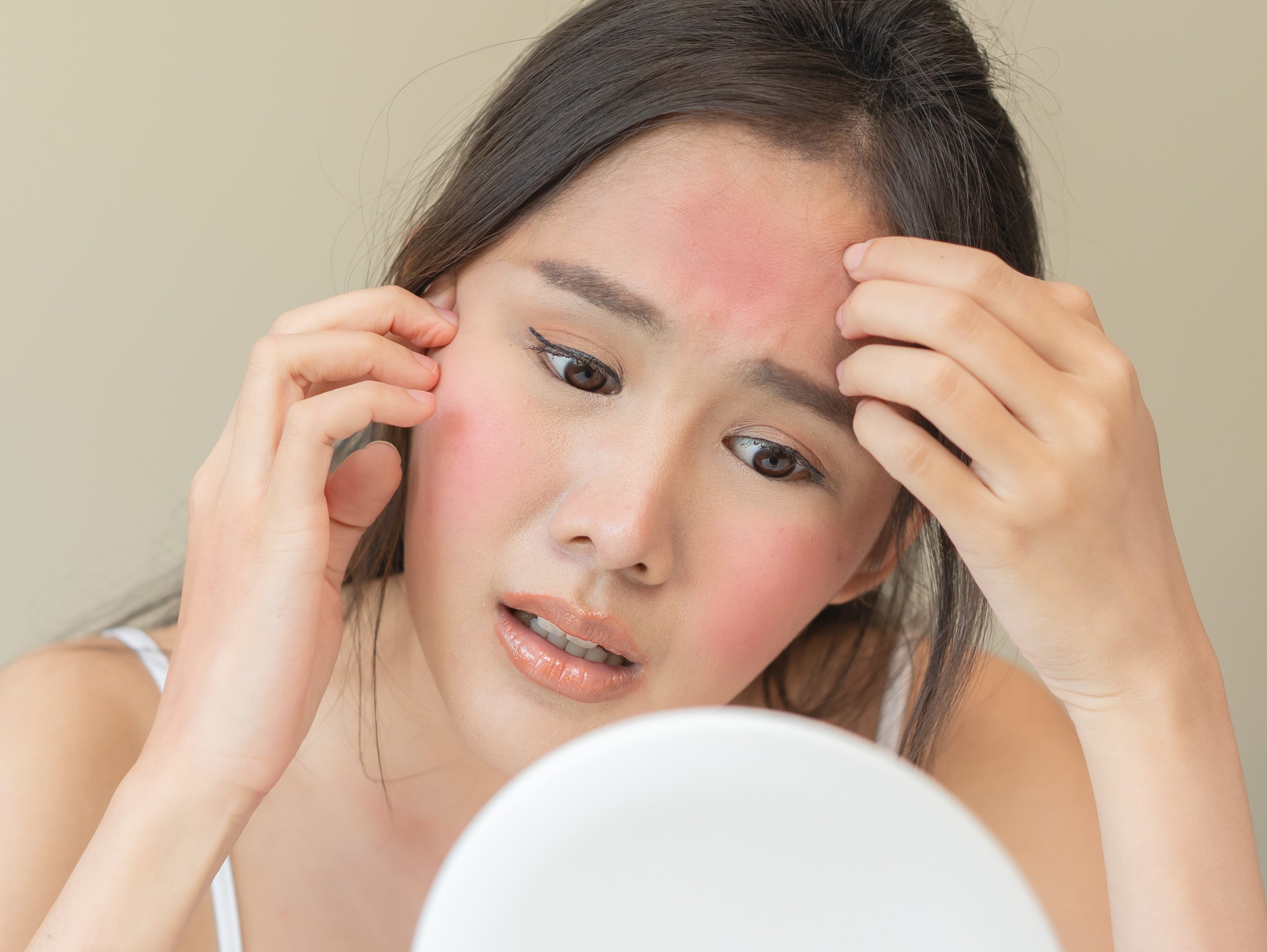Close-up of young woman examining skin