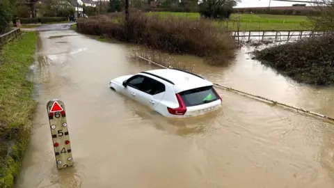 Floodwater surrounding parked cars