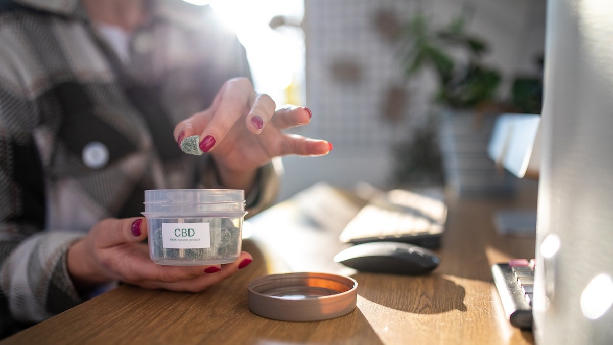 Jar of CBD gummies next to a pregnant woman's hand