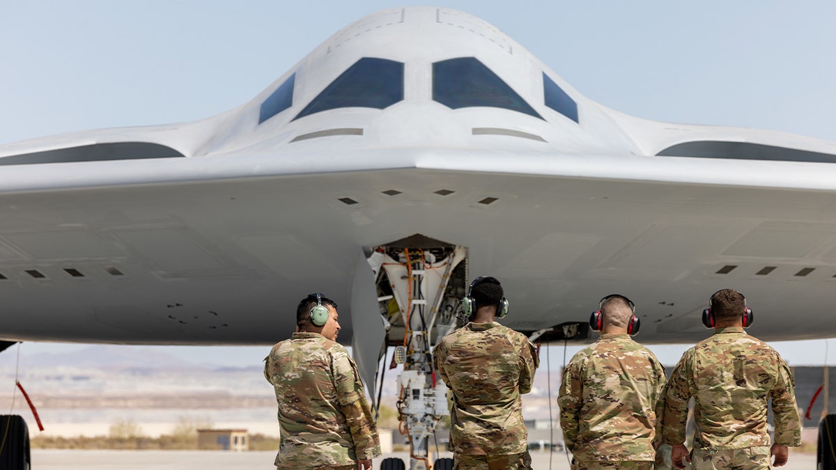 Airmen near a B-21 in a hangar