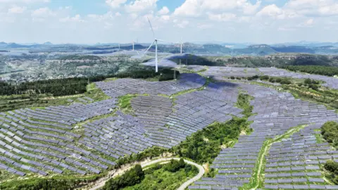 Solar panels and factory silhouette