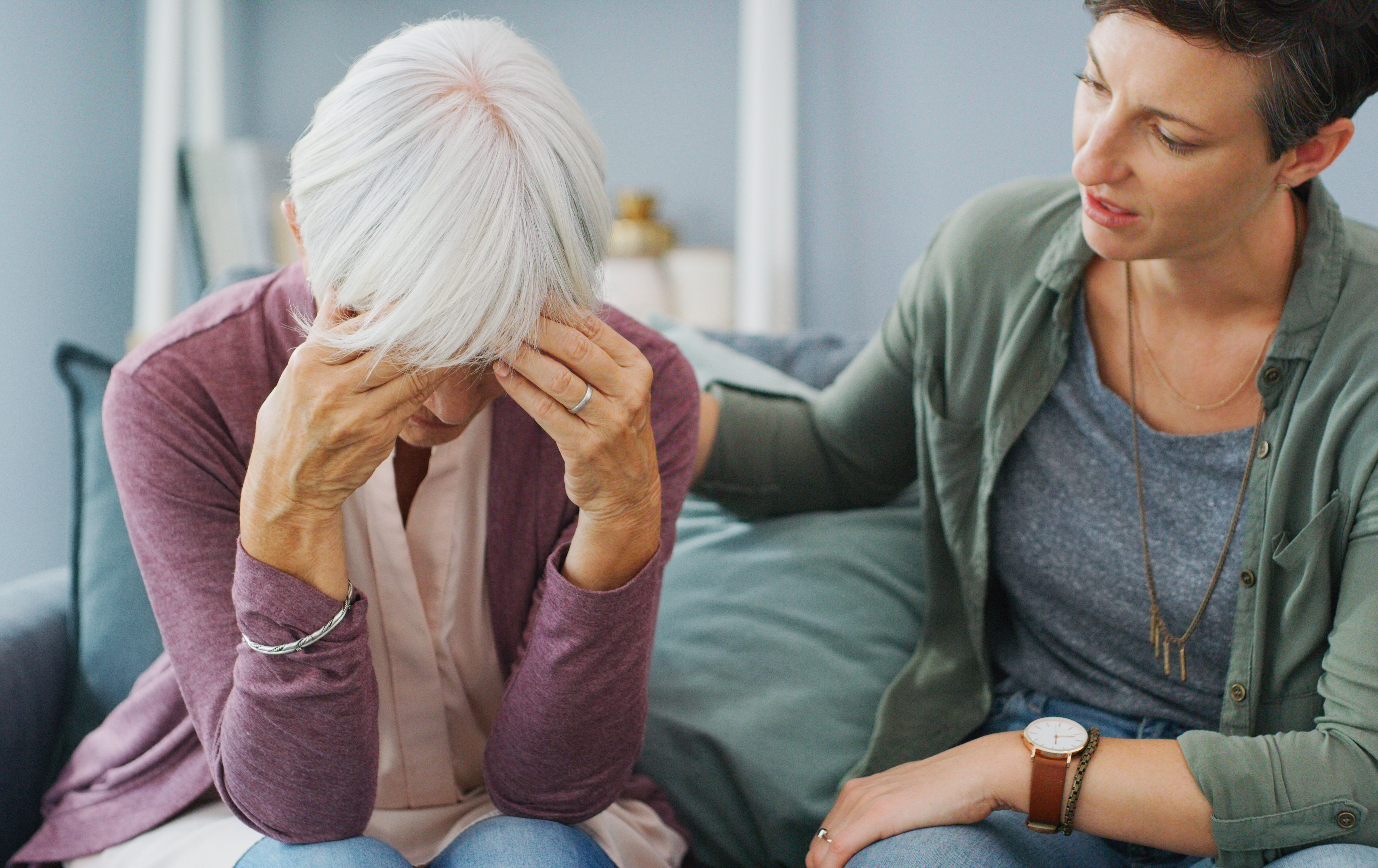 Stressed older adult with family member offering support