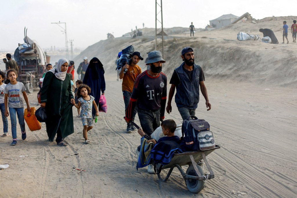 Displaced Palestinians fleeing northern Gaza crowd near a truck