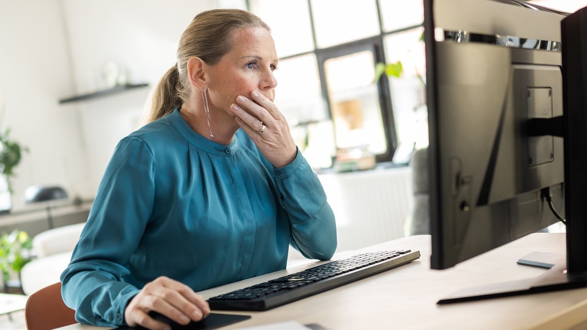 Person at a desk holding their head, appearing stressed