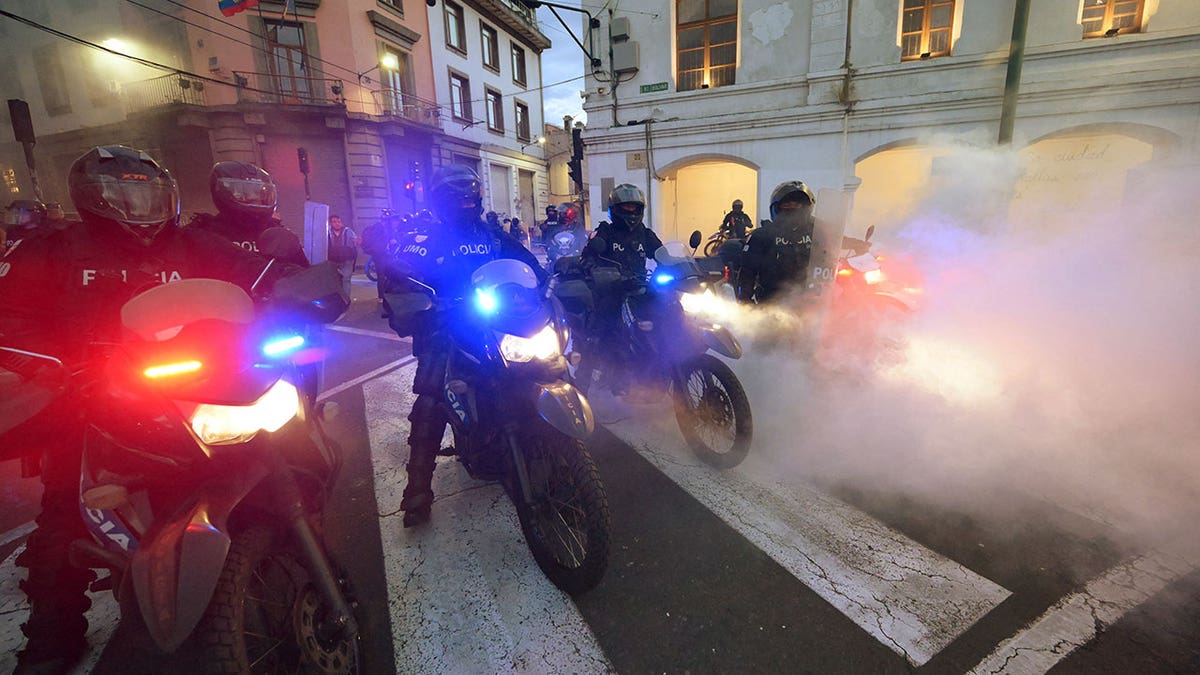 Police officers stand guard during a protest in Quito