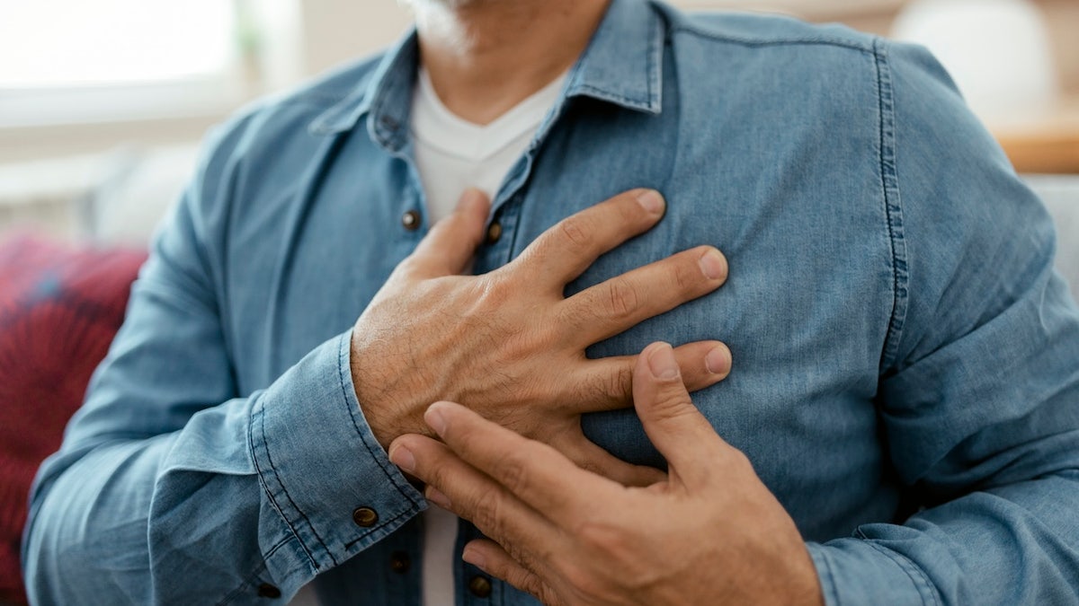 Man holding chest, indicating heart pain