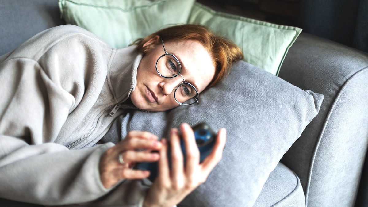 Woman very tired, laying with phone