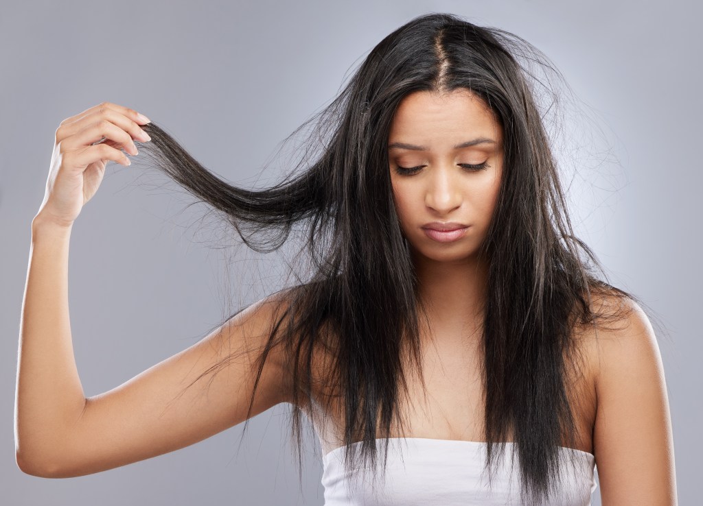 Woman with damaged hair touching her face