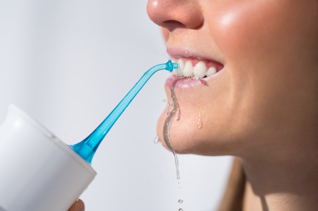 Woman using a water flosser for oral hygiene