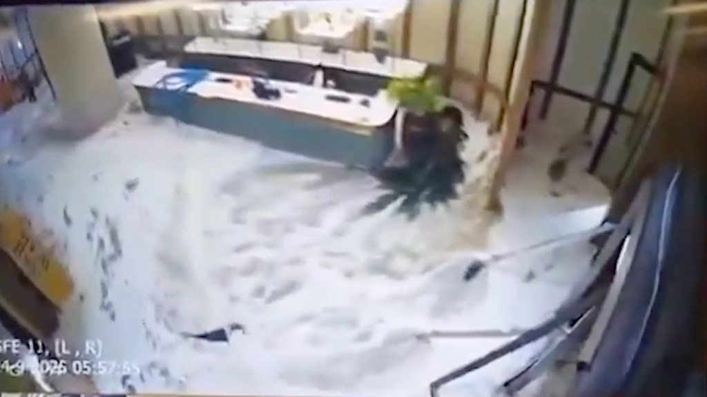 Murky floodwaters rush through hotel doors