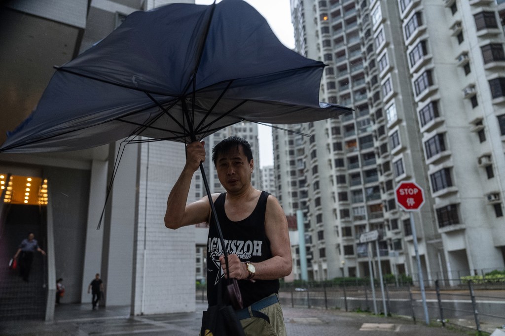 Pedestrian holds an umbrella under strong wind in Heng Fa Chuen