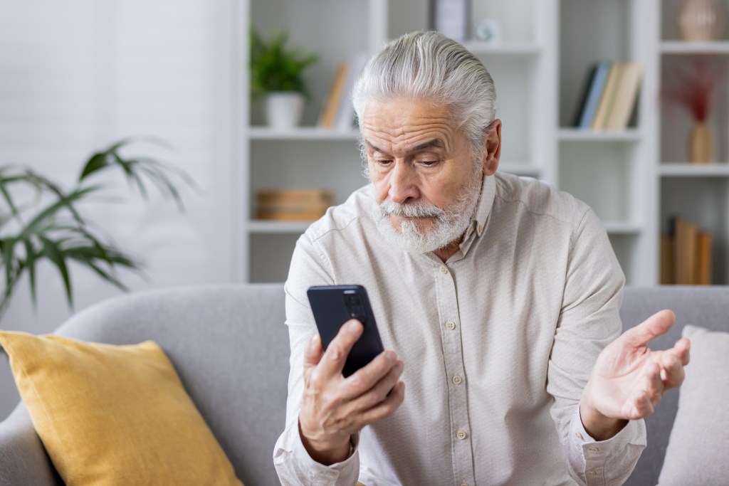 Older adult using a phone on a couch