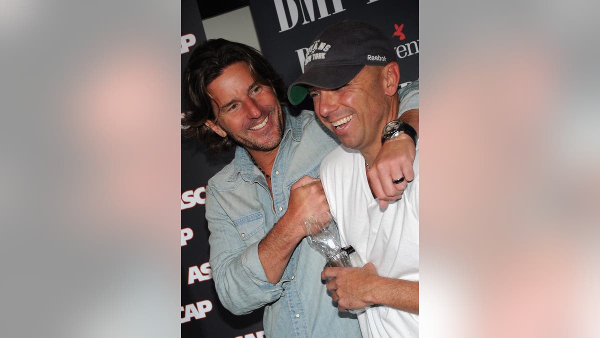 Brett James and Kenny Chesney hugging onstage